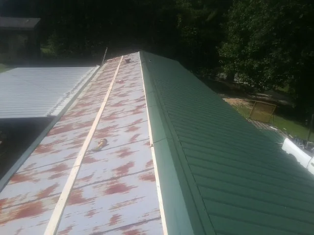 Old rusted panels beside newly installed green metal roofing — Wind Damage Roof Repair by Roofing Brothers in East Rochester