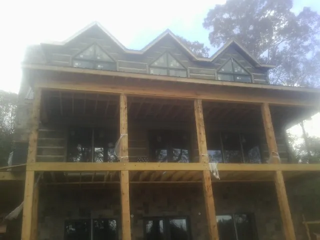Dormers and porch framing on a large log home under construction — Roof Coating work by our crew in East Rochester