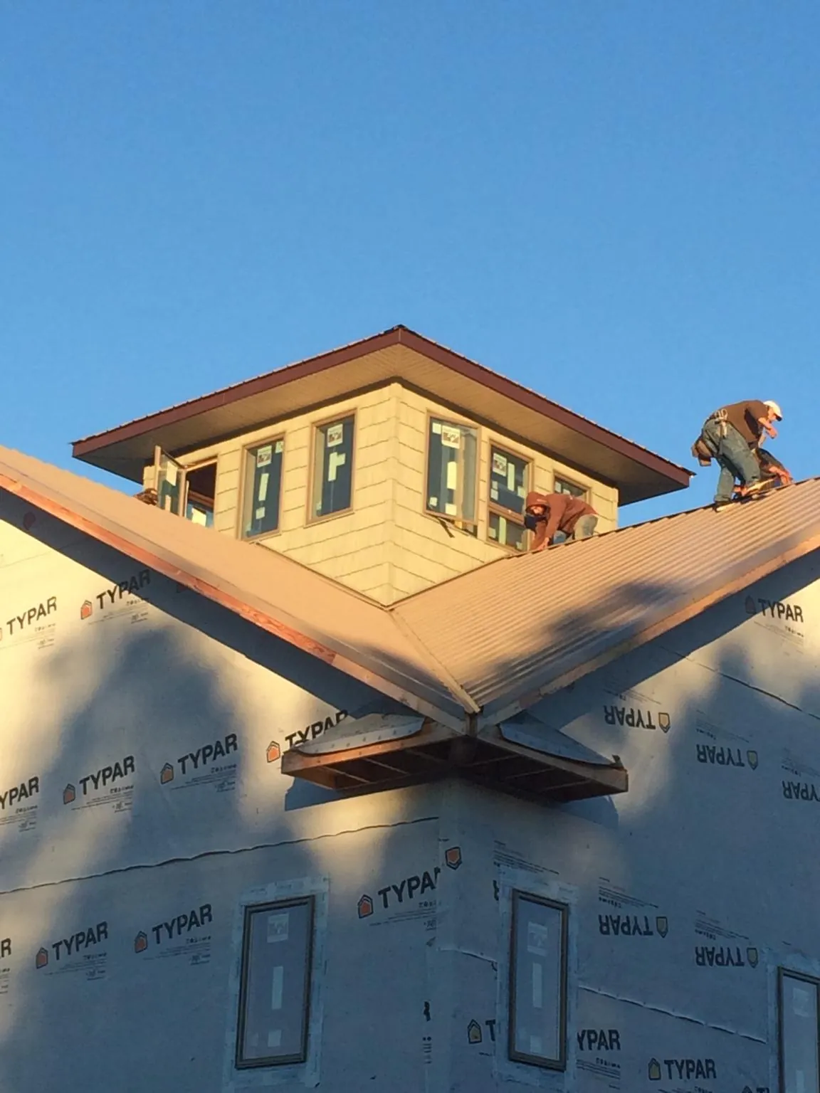 Roofers working around a rooftop cupola on a new metal roof at sunset — Roof Waterproofing in East Rochester by Roofing Brothers